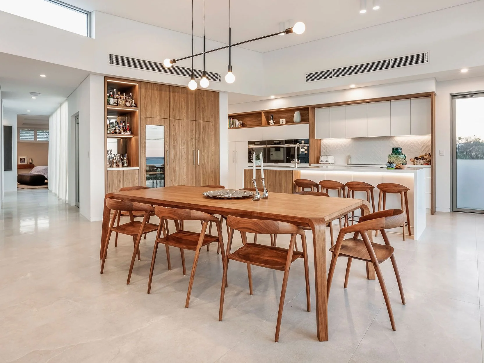 Araluen Table in Walnut styled in an open-plan kitchen and dining space with timber chairs - Nathan Day Design