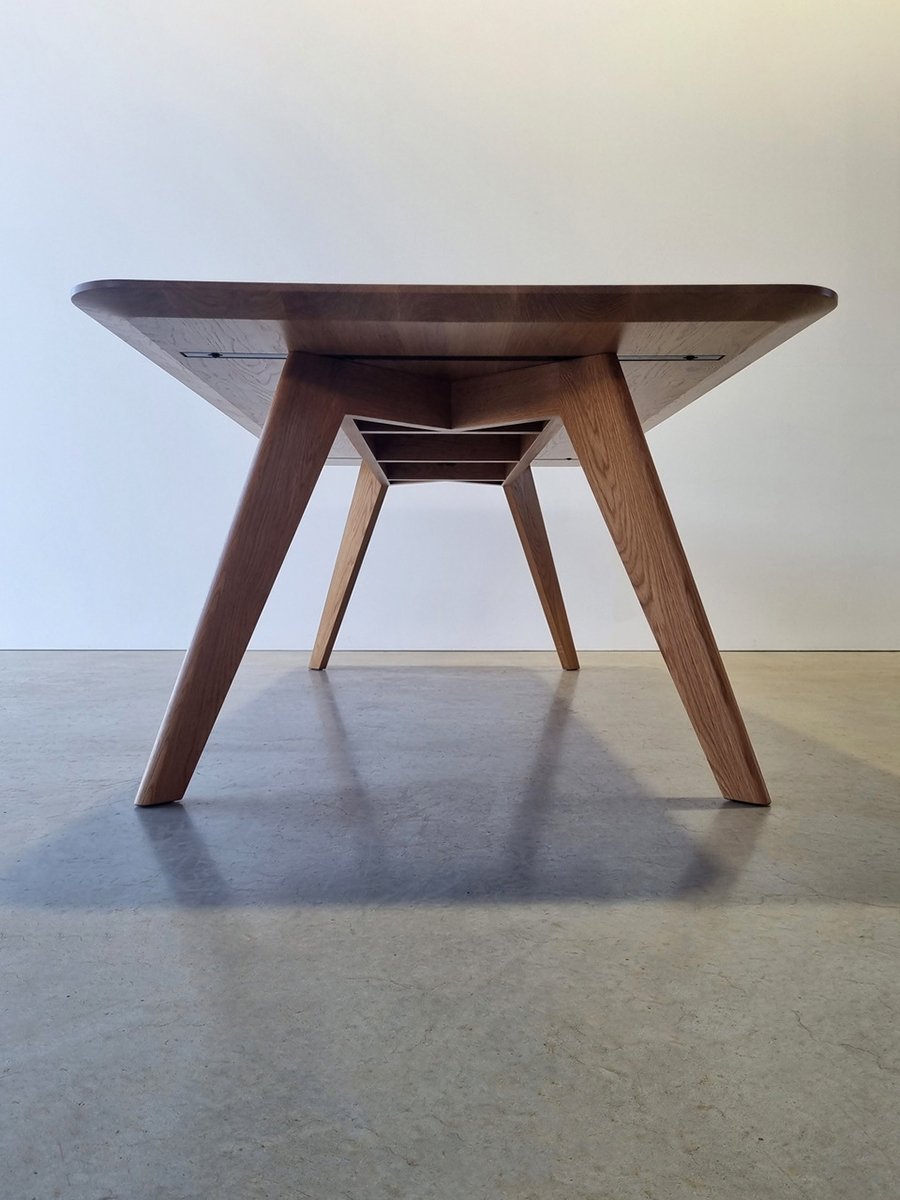 End-on view of Vista St Table in Oak showing splayed dovetail leg base structure - bespoke furniture by Nathan Day Design