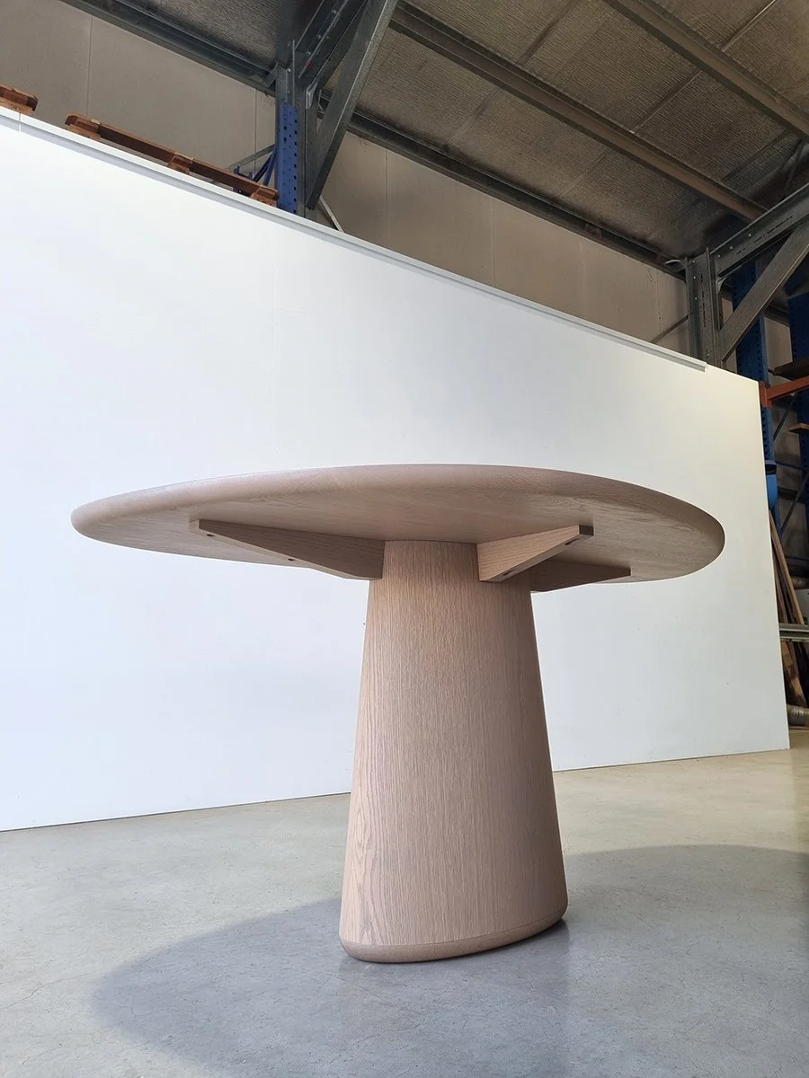 Angled view of Pebble Table showing integrated cross-brace under tabletop and conical tapered pedestal - bespoke furniture by Nathan Day Design