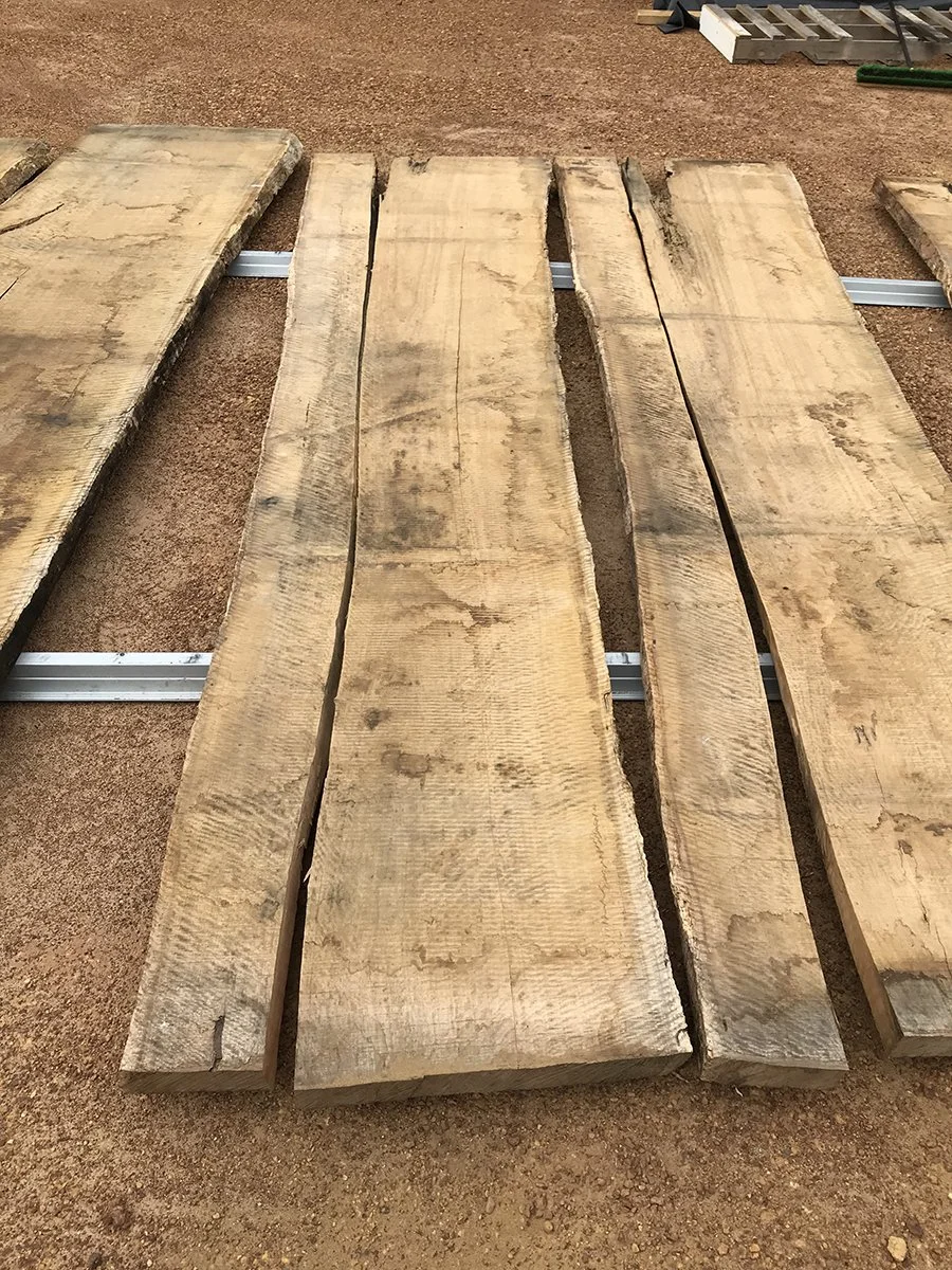DWER custom furniture in WA Blackbutt - Nathan Day Design, raw timber slabs stacked outdoors before milling