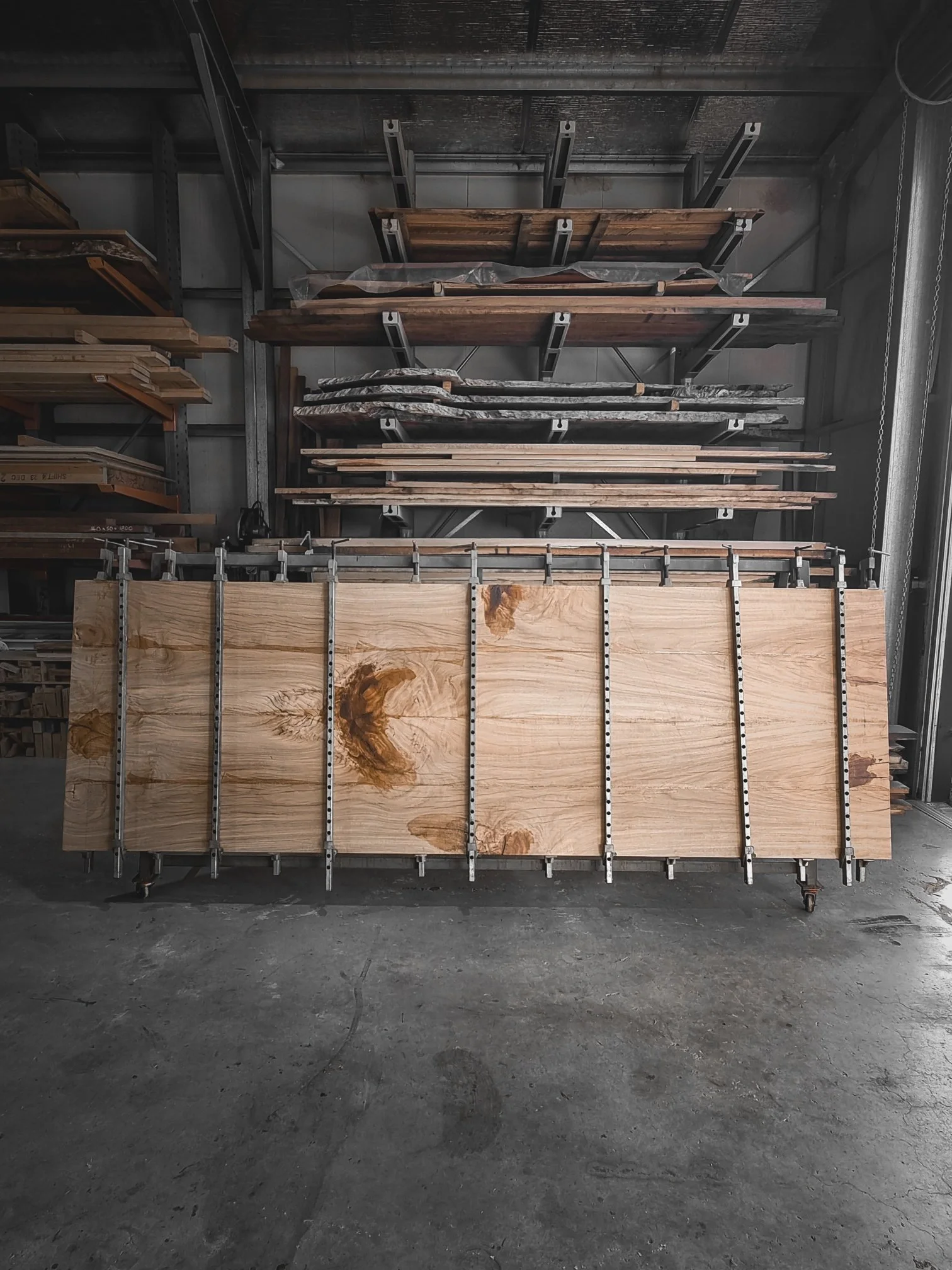 A live-edge timber slab clamped and stored on a workshop rack at Nathan Day Design