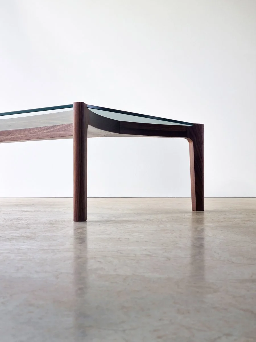 End-on eye-level view of the Wende Coffee Table showing the American Walnut frame and glass tabletop - Nathan Day Design