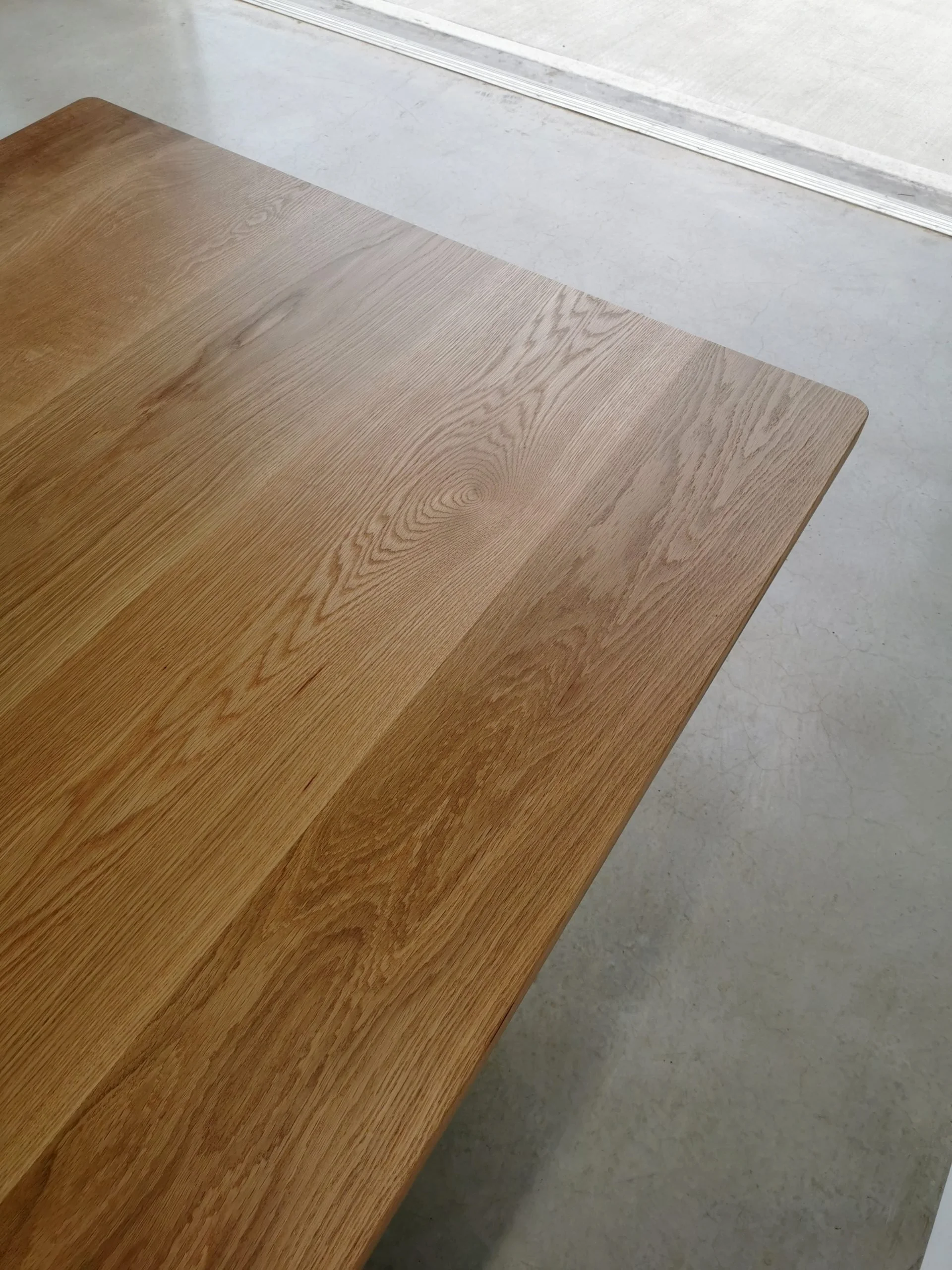 Close-up of Clairault Table's American Oak tabletop corner showing rich grain and clean mitred edge - bespoke furniture by Nathan Day Design