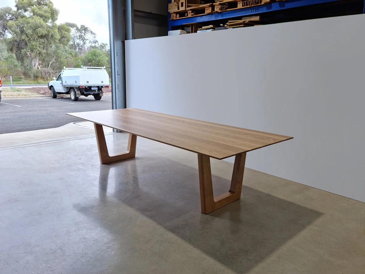 Clairault Table in American Oak with distinctive trapezoidal leg frames, near workshop doorway - bespoke furniture by Nathan Day Design