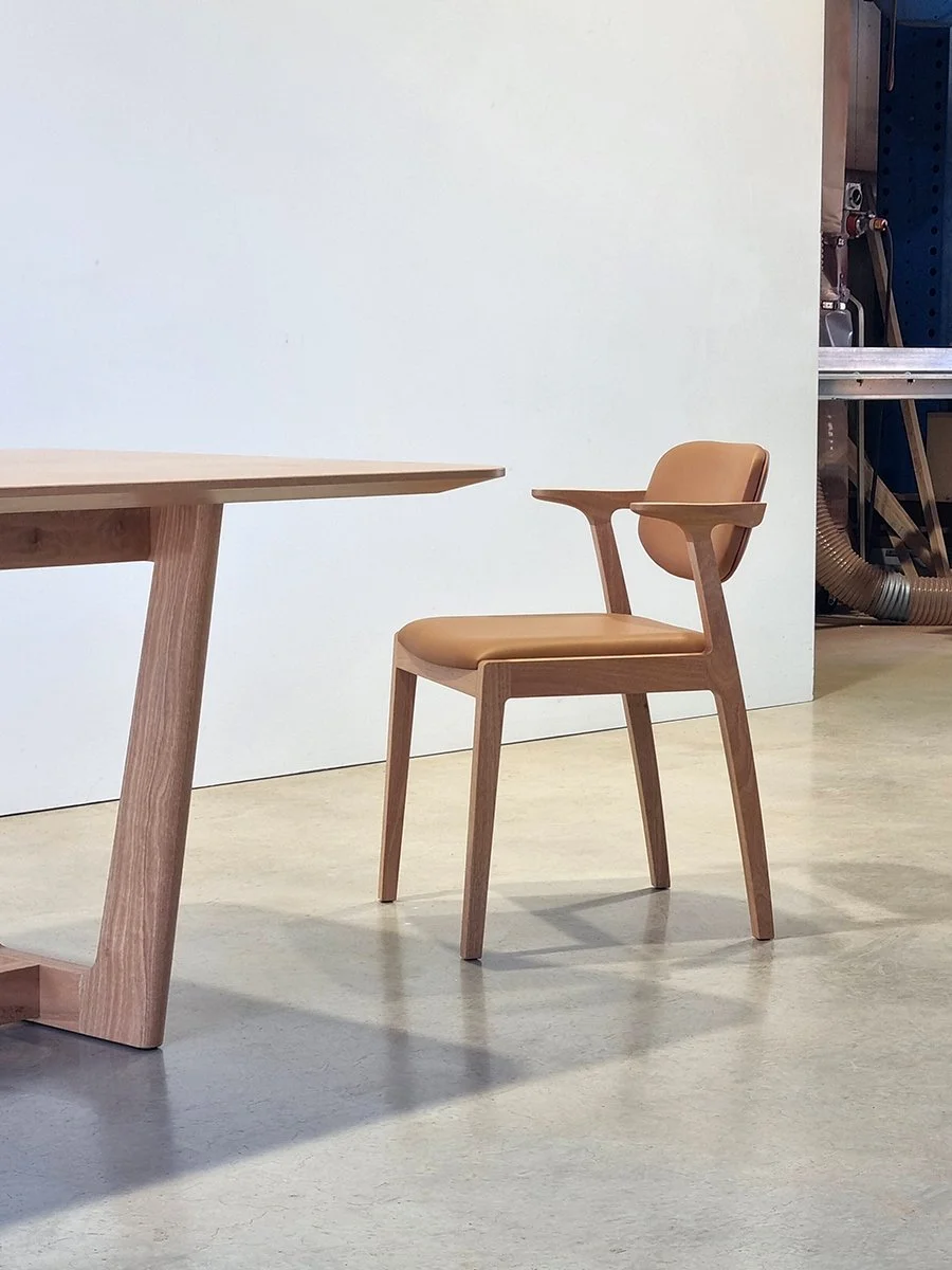 Botanical Table corner in Walnut paired with tan leather dining chair, workshop setting - bespoke furniture by Nathan Day Design