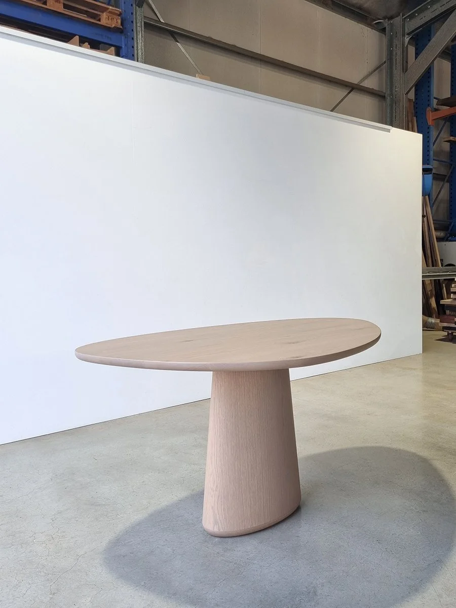 Pebble Table in grey-tinted American Oak with organic pebble-shaped top and tapered pedestal base, workshop setting - bespoke furniture by Nathan Day Design