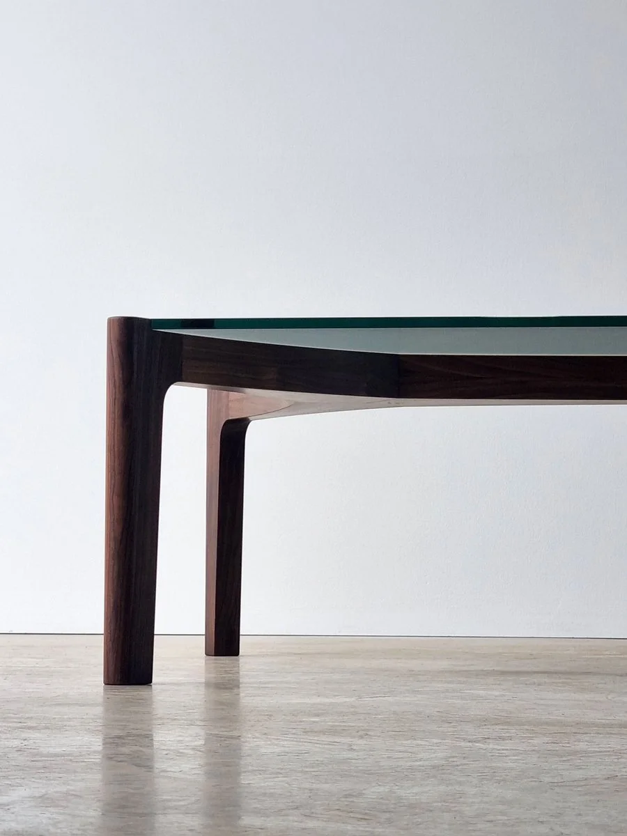 Low angle view of the Wende Coffee Table's dark walnut leg frame and precision-fitted glass top - Nathan Day Design