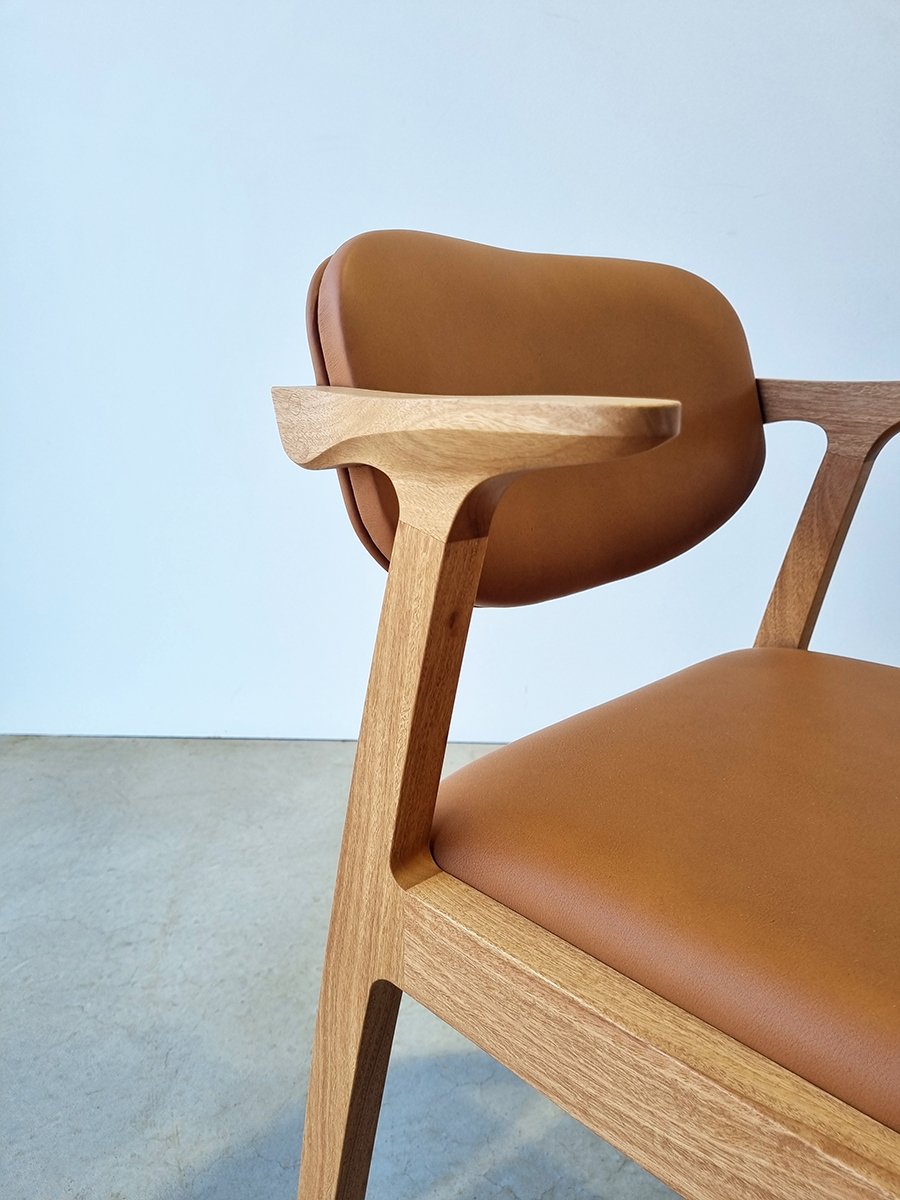 Angled close-up of Kinross Chair in American Oak showing the sculptural backrest curve and armrest form - bespoke furniture by Nathan Day Design