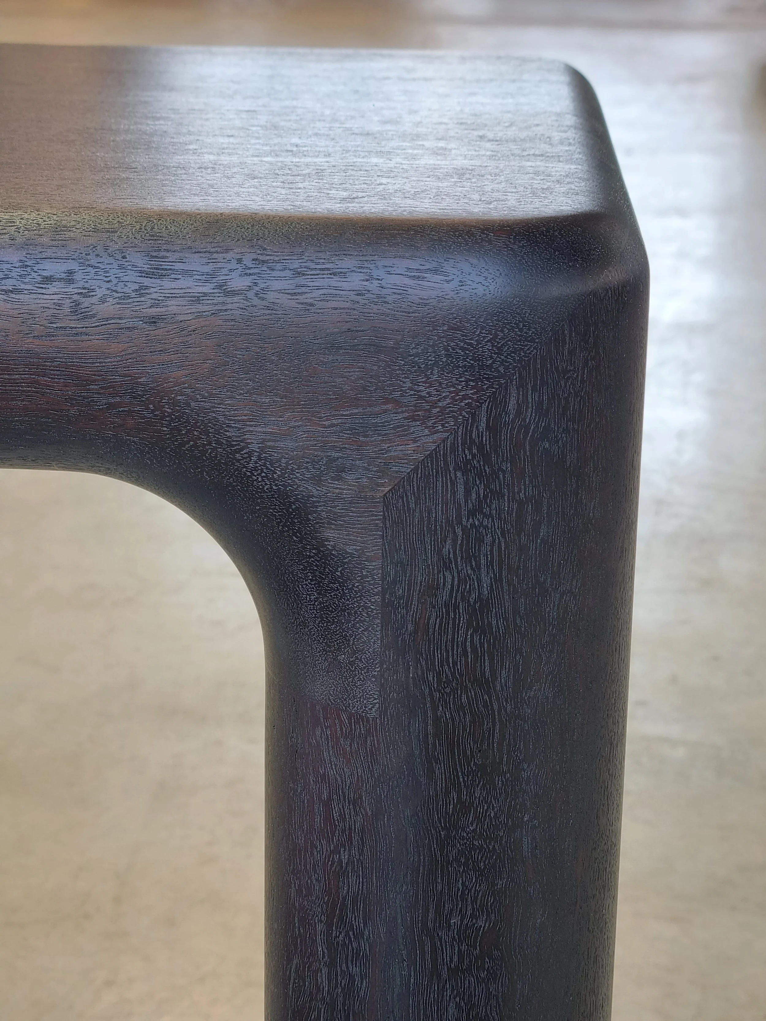Close-up detail of Hippo Bench's Ebonised Jarrah leg corner showing the sculpted rounded profile - bespoke seating by Nathan Day Design