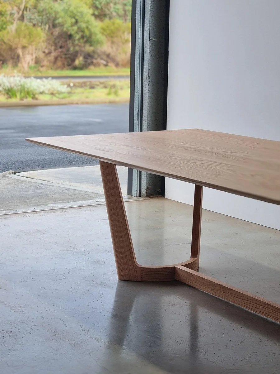Froxfield Table in French Oak, angled corner view near an open workshop door - Nathan Day Design