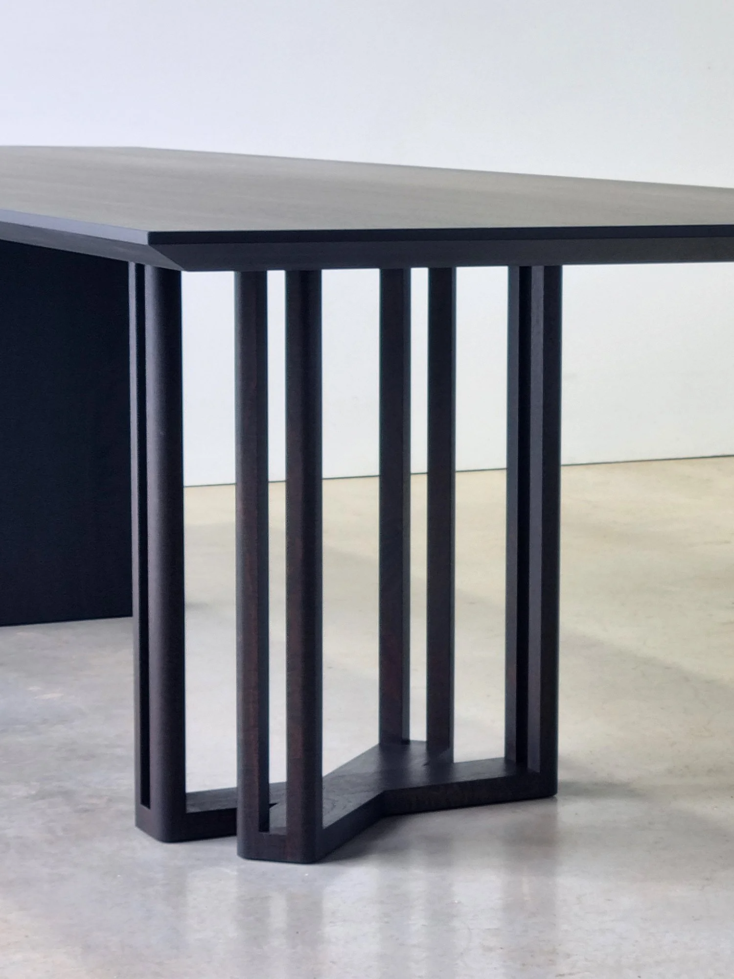Close-up of the Giacci Table's delicate multi-slat leg in ebonised Walnut - Nathan Day Design