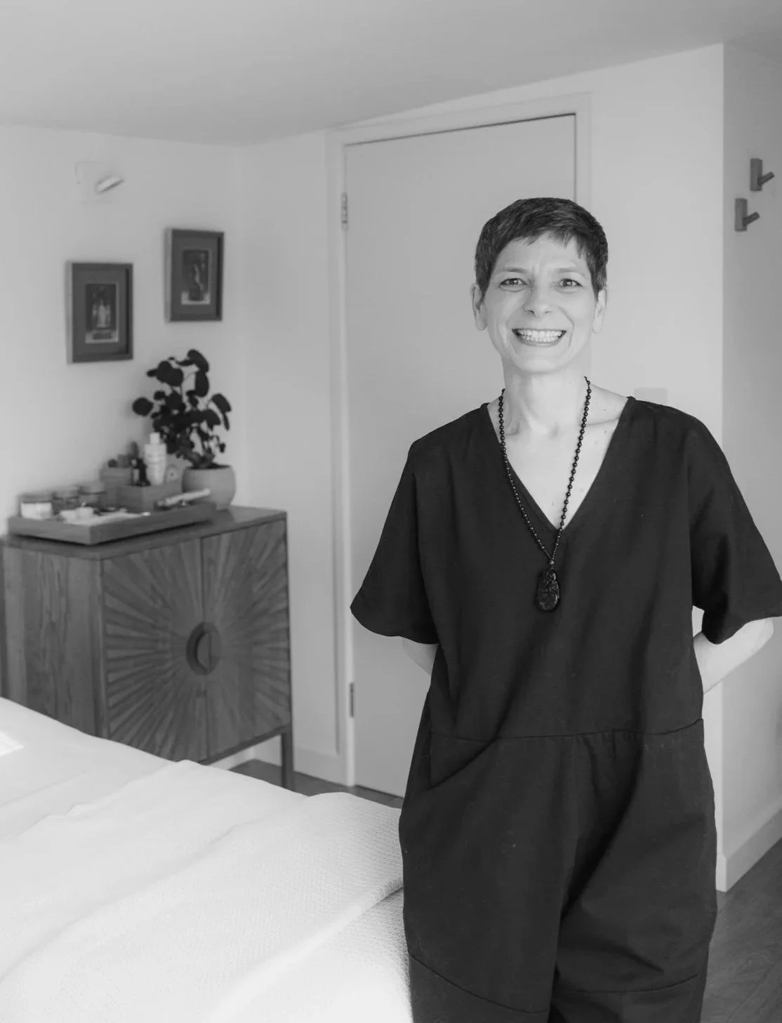 Acupuncturist Kerstin Lehr wearing black dress standing in acupuncture studio smiling
