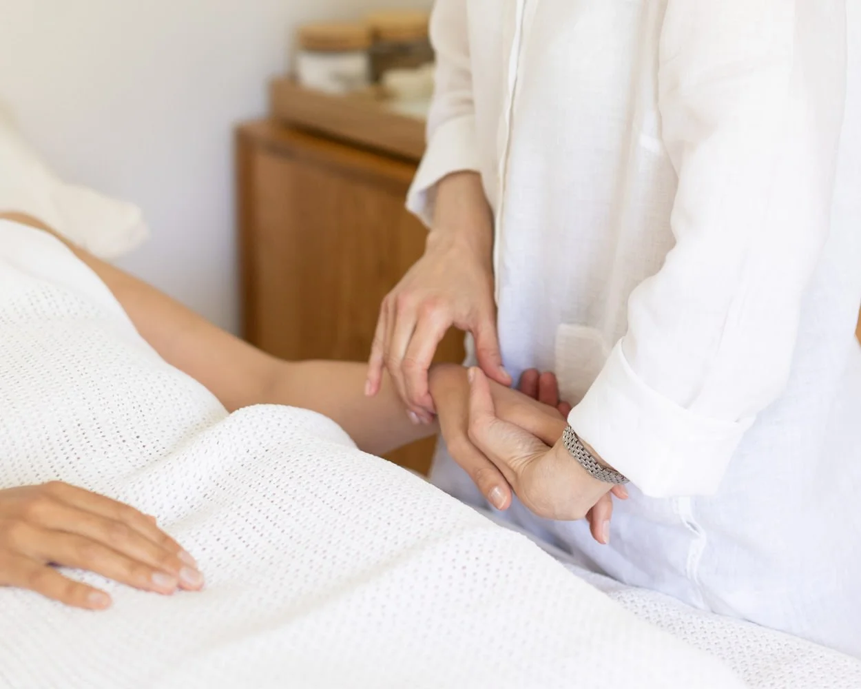 Kerstin Lehr acupuncturist  holding a patient’s hand on a treatment couch