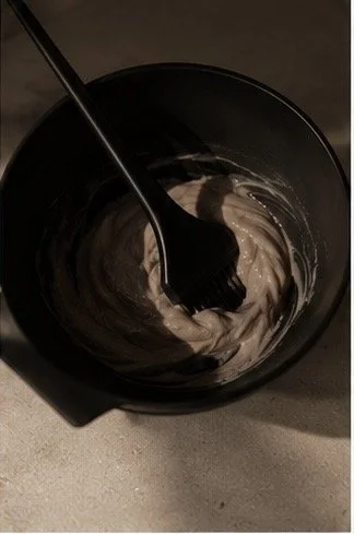 A black mixing bowl with a spoon and some light-colored batter or mixture inside.