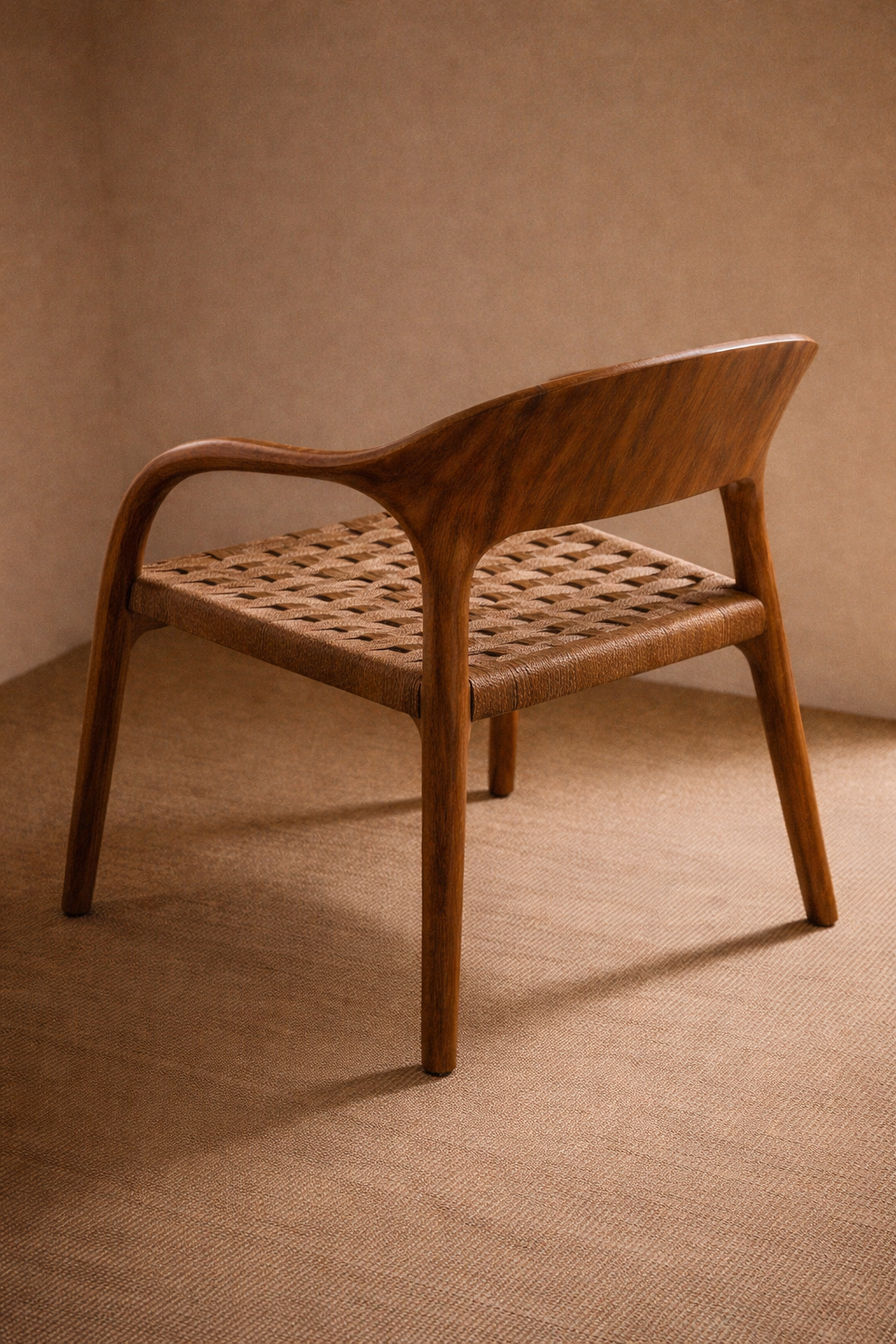 A wooden chair with a woven seat, curved backrest, and four angled legs, placed on a beige carpet with a plain beige wall background.