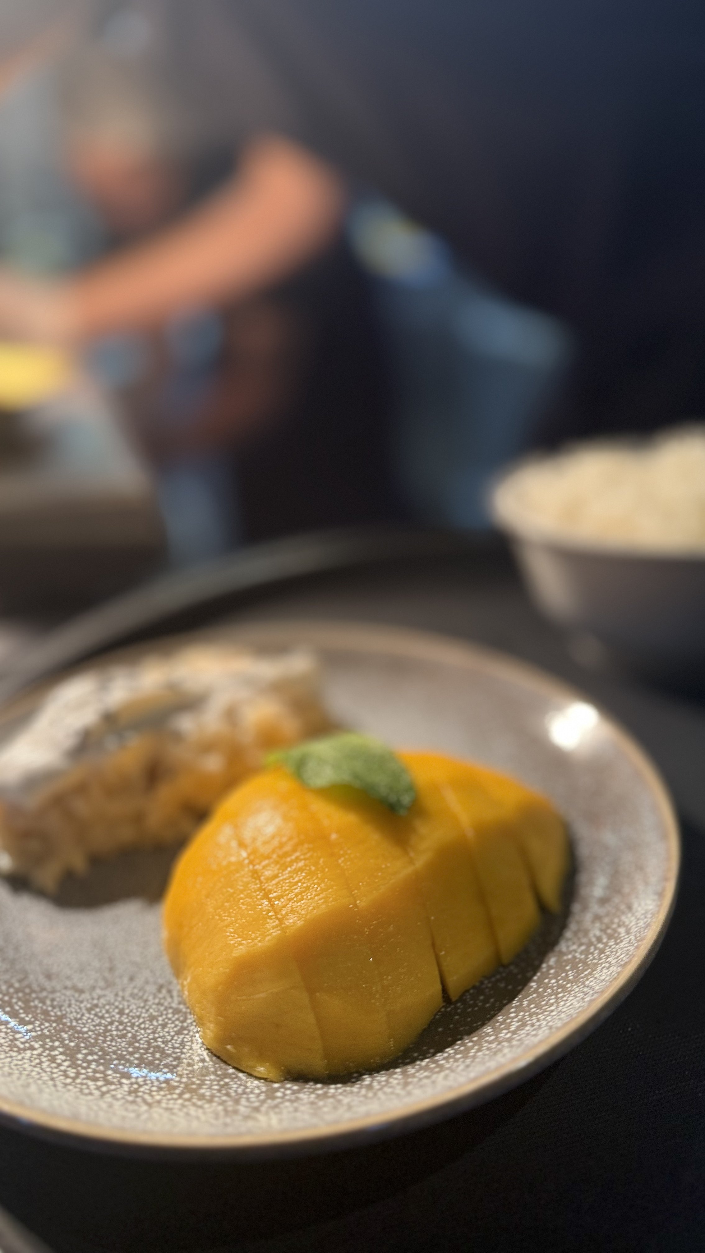 mango sticky rice: une mangue coupée en longueur avec une feuille verte sur le dessus, servie avec du riz gluants