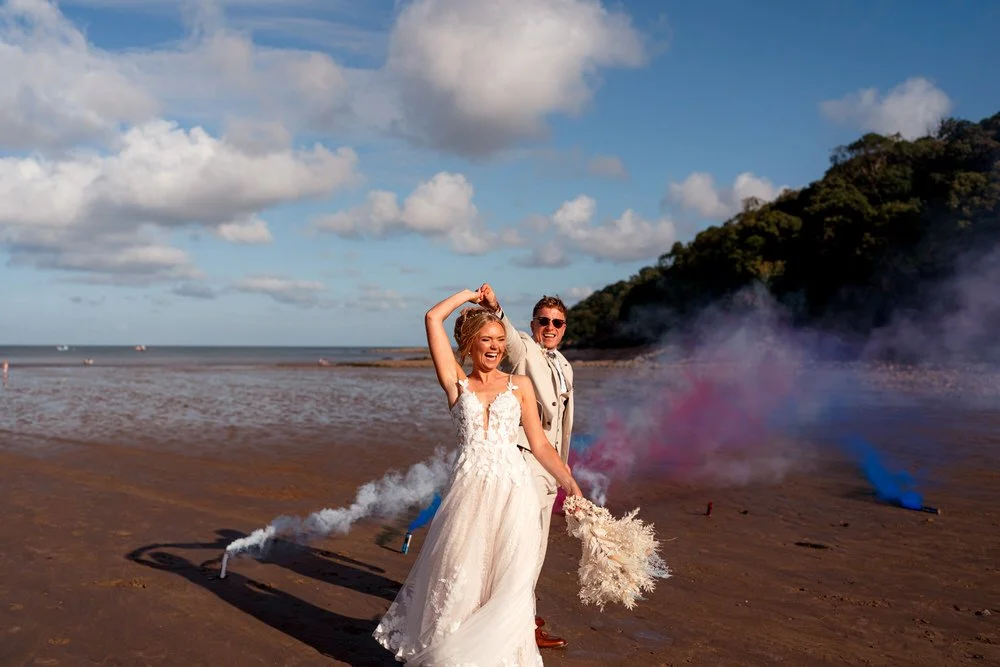 Newly married couple dancing on Oxwich Bay Beach on their wedding day, surrounded by smoke bombs in Swansea, South Wales