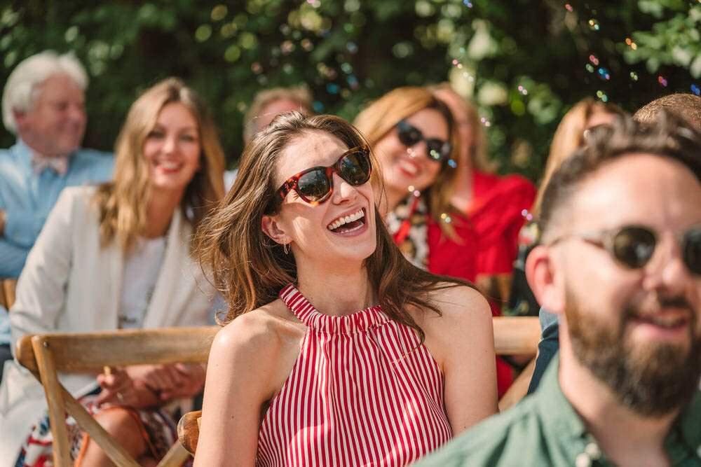 Natural wedding photography, candid guest laughing image during an outdoor handfasting ceremony at the Anrán wedding venue in Dorset. 
