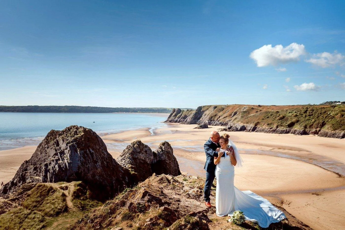 Three Cliffs wedding photographs of an adventurous bride and groom holding each other on the dramatic cliff top, taken from Southgate Cliffs. 