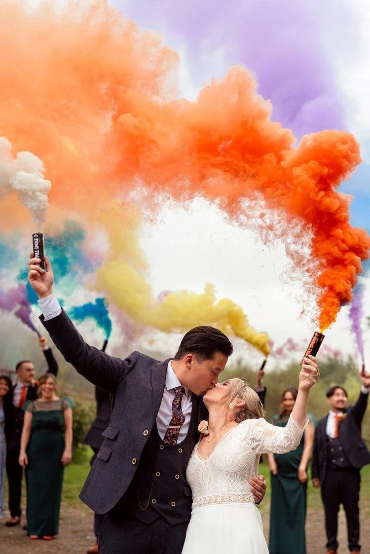 Colourful smoke bomb photograph, exploding multi colours whilst the bride and groom kiss at their wedding celebrations at the Ceridwen Centre in Carmarthenshire. 