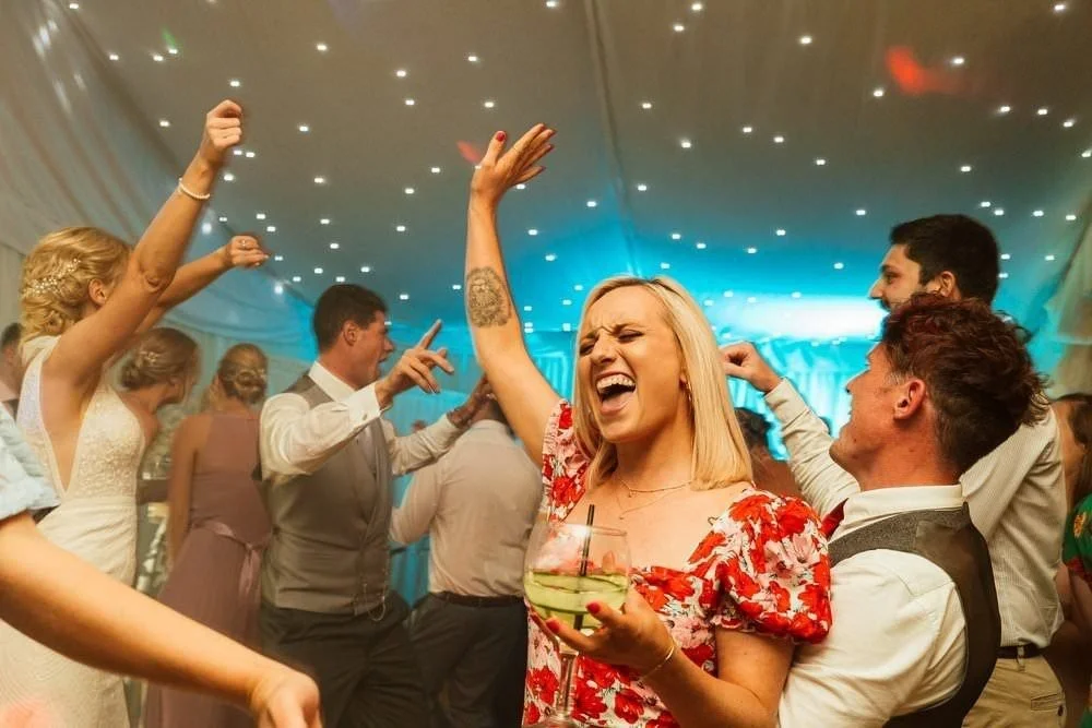 Dancefloor antics photographed at Ocean View wedding venue in Gower, South Wales. Revellers throwing their arms in the air, dancing after the first dance. 