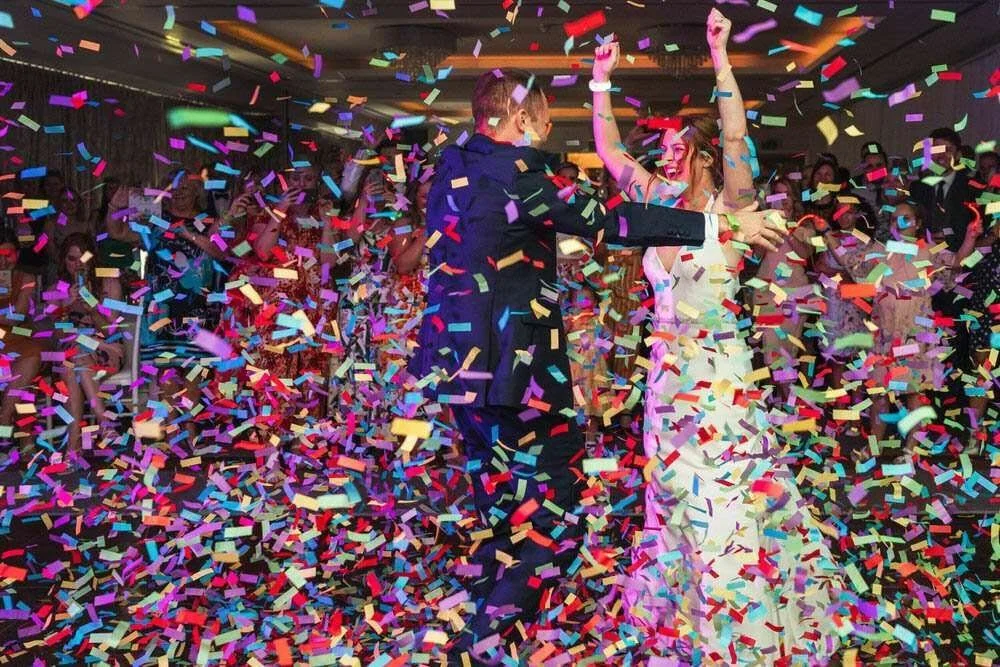 First dance photographs filled with confetti flying over the newlywed bride and groom as confetti cannons explode during their first dance at Hensol Castle in the Vale Resort, Cardiff. 