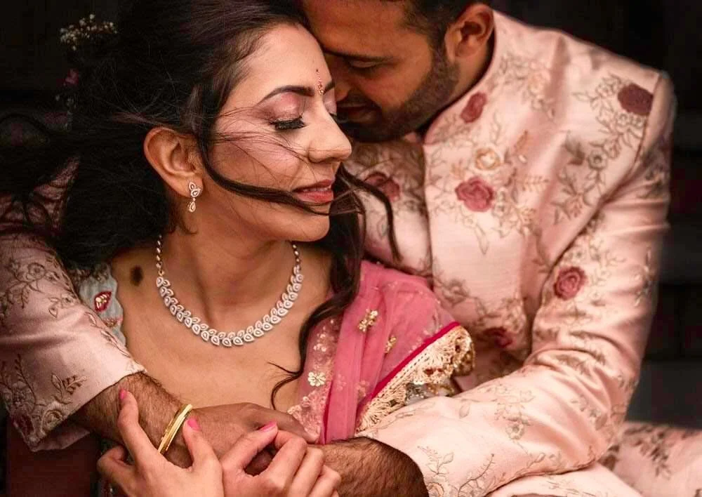 Roka ceremony Indian couple photographed during their wedding ceremony in Swansea. Wearing tones of pink, the colourful couple holding each other with the wind blowing the brides hair.