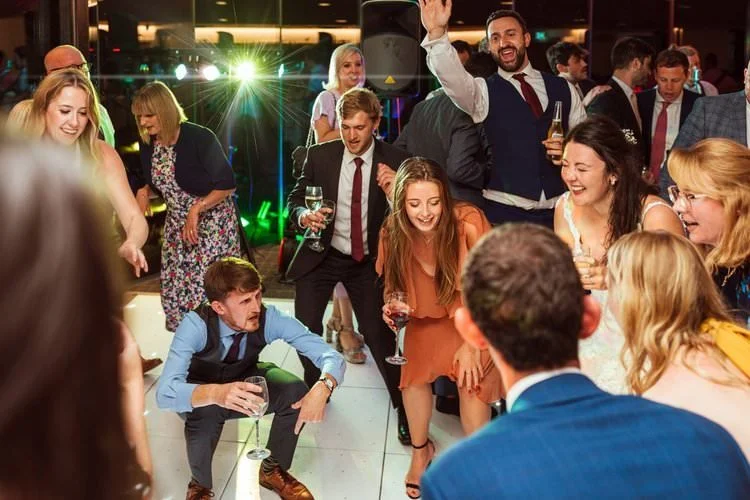 Dancefloor in action photo at Fairyhill, Swansea. Wedding guests with the laughing bride getting down low, dj and lights in the background. 