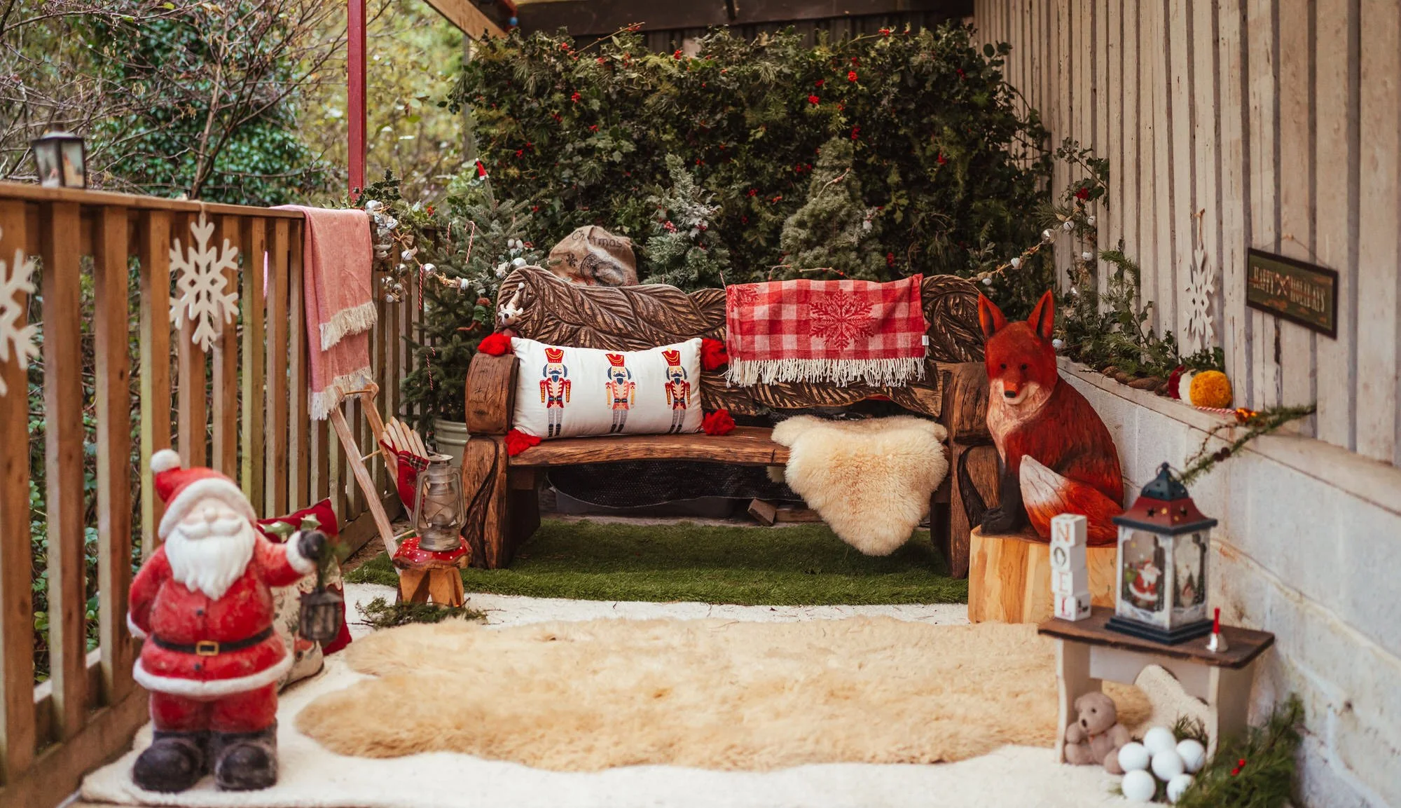 Christmas photo shoot set with a festive look, real trees in snow, a wooden bench and blankets.