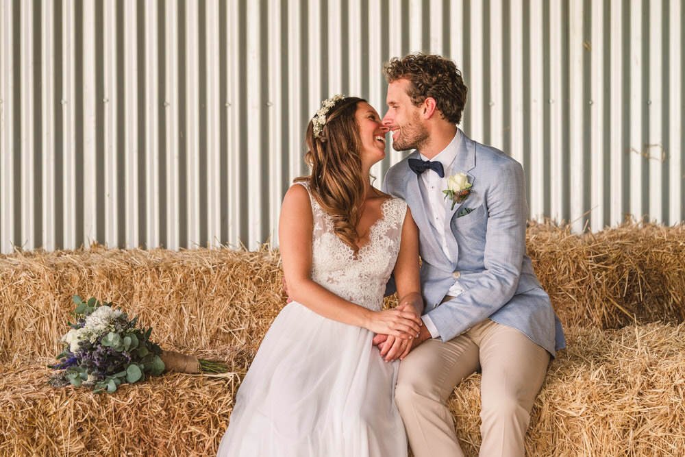 Bride and groom kissing on hay bales