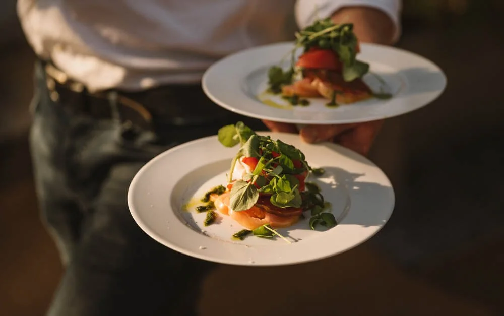 Waiter carrying two tomato and mozzarella starter plates