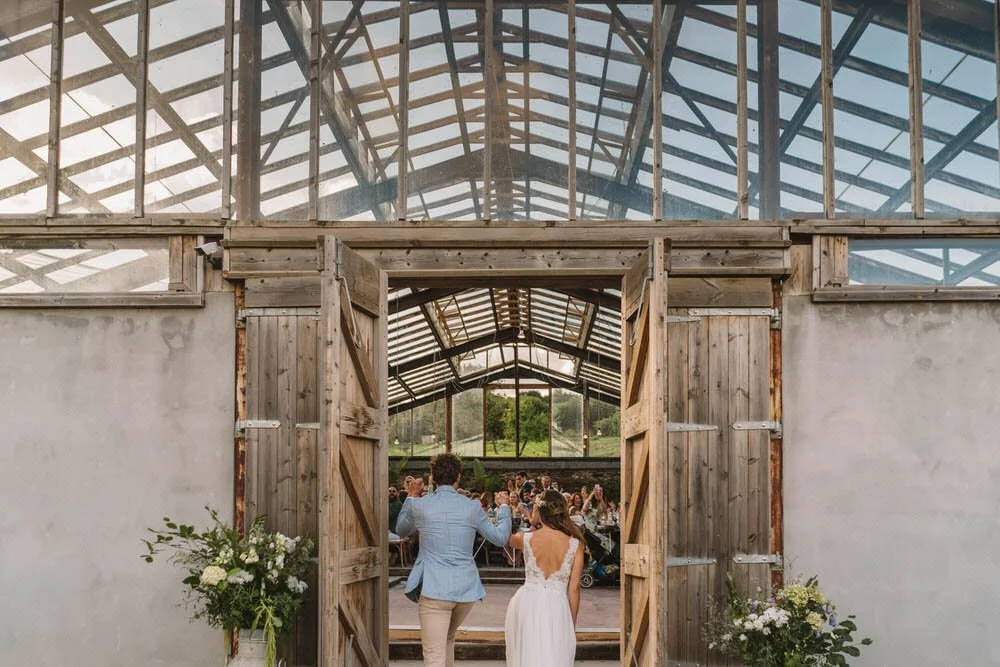 bride and groom entering glass house barn
