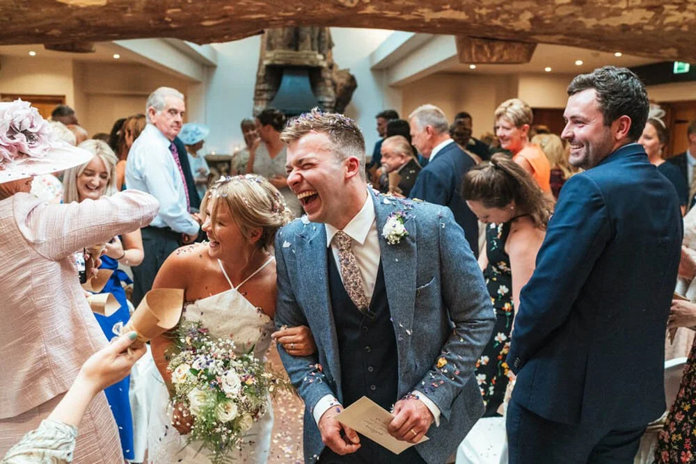 Happy wedding couple walking back down the aisle after getting married at the Oxwich bay hotel in Swansea. Confetti being thrown over the couple.