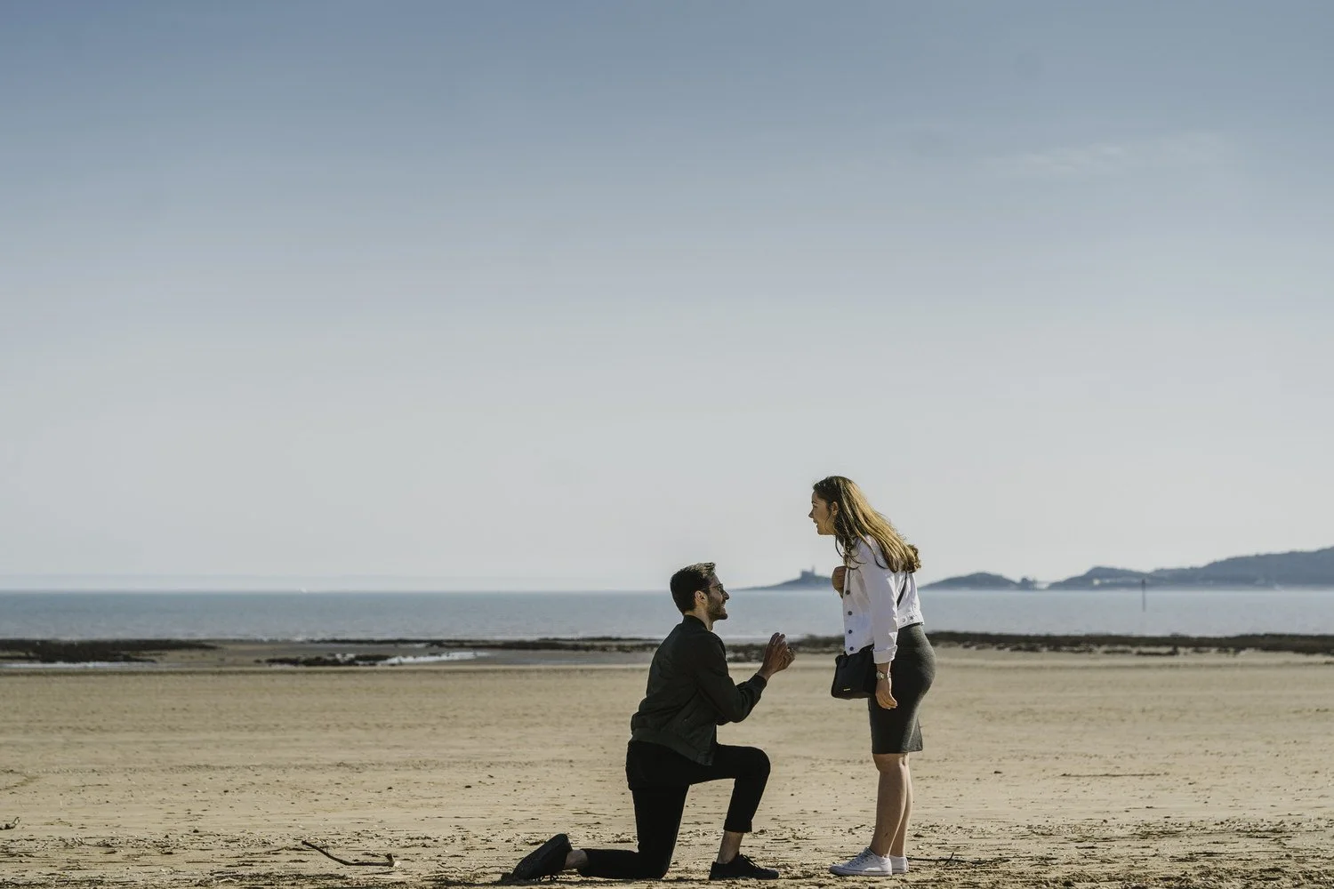 Man down on one knee proposing marriage to his girlfriend on Swansea bay.