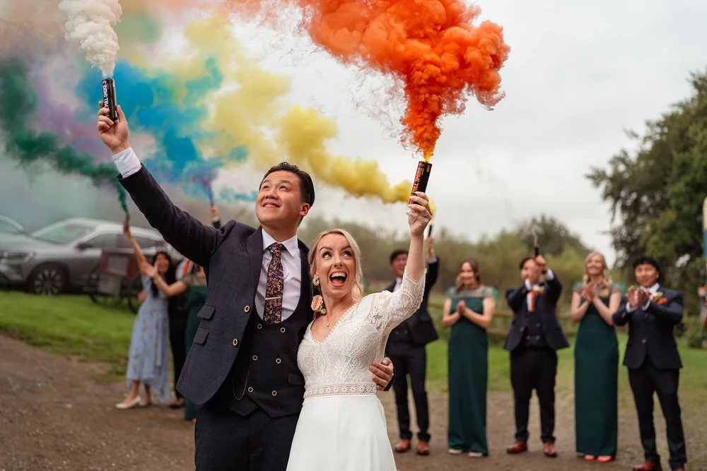 Wedding couple with colourful smoke bombs at the Ceridwen Centre in South Wales for their wedding photos with their bridesmaids and groomsmen.
