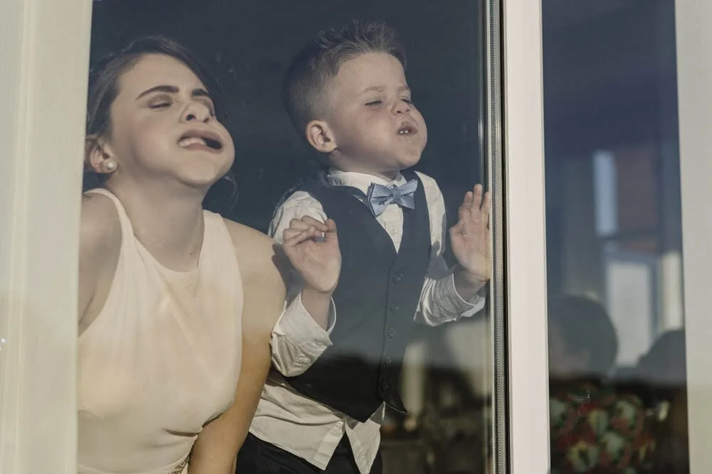 Young bridesmaid and page boy having fun at a wedding reception in Swansea, blowing raspberries onto the window