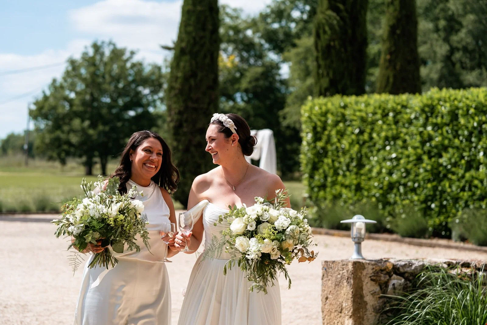 Two brides holding bouquets walking through the Chateau De Sanse in France