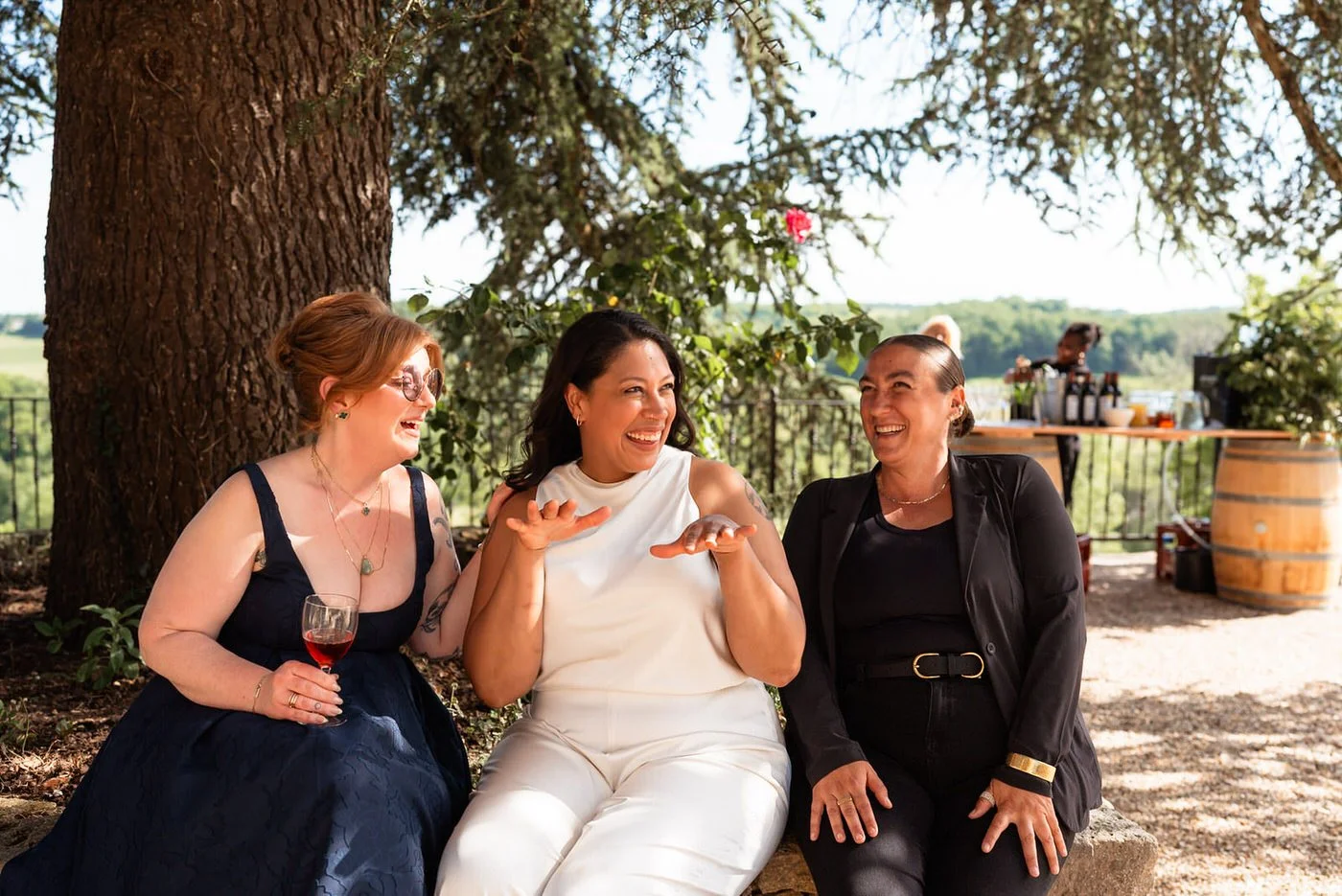 wedding guests laughing and having fun with a bride sat inbetween them, a candid moment at the Chateau De Sanse.
