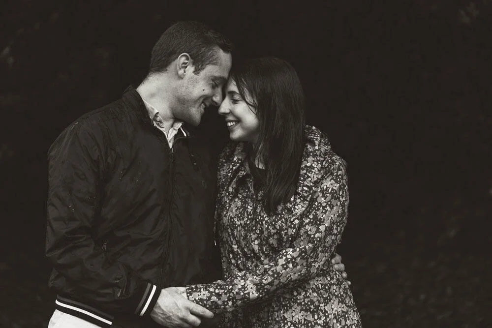Engaged couple having their engagement shoot in Singleton Park Swansea. The couple embracing under a tree in the rain.
