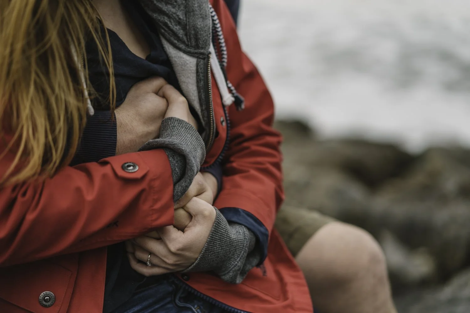 Tight embrace of a couple on a beach in the rain.