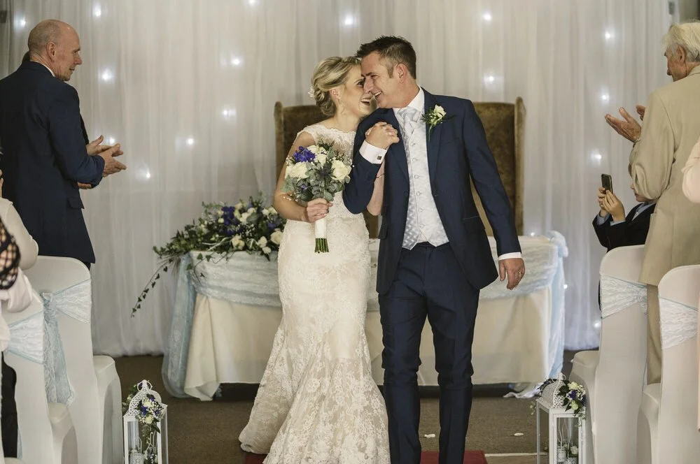 Happy couple just pronounced husband and wife during their wedding ceremony leaning into each other about to walk back down the aisle at Plas Hyfryd hotel in Narberth.