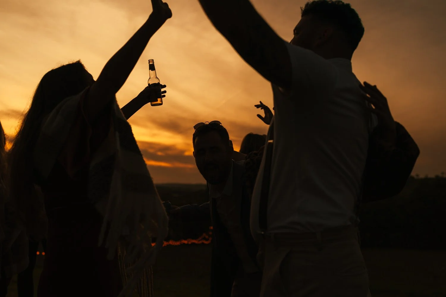 Silhouette of wedding guests parting at sunset in the grounds at the Ceridwen Centre in Carmarthenshire during a wedding party.