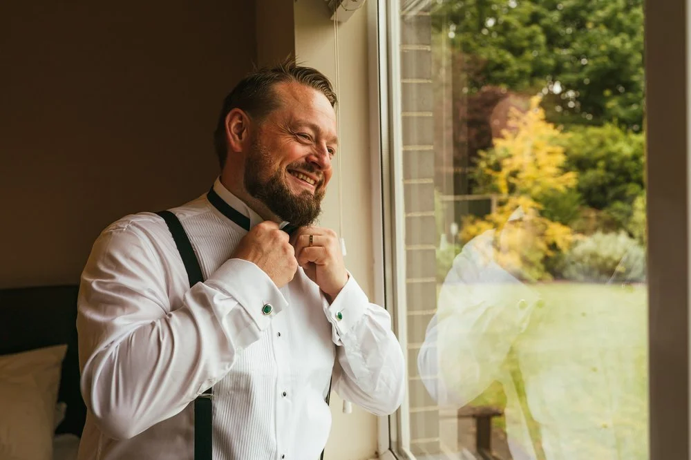 Grooms reflection in window getting ready