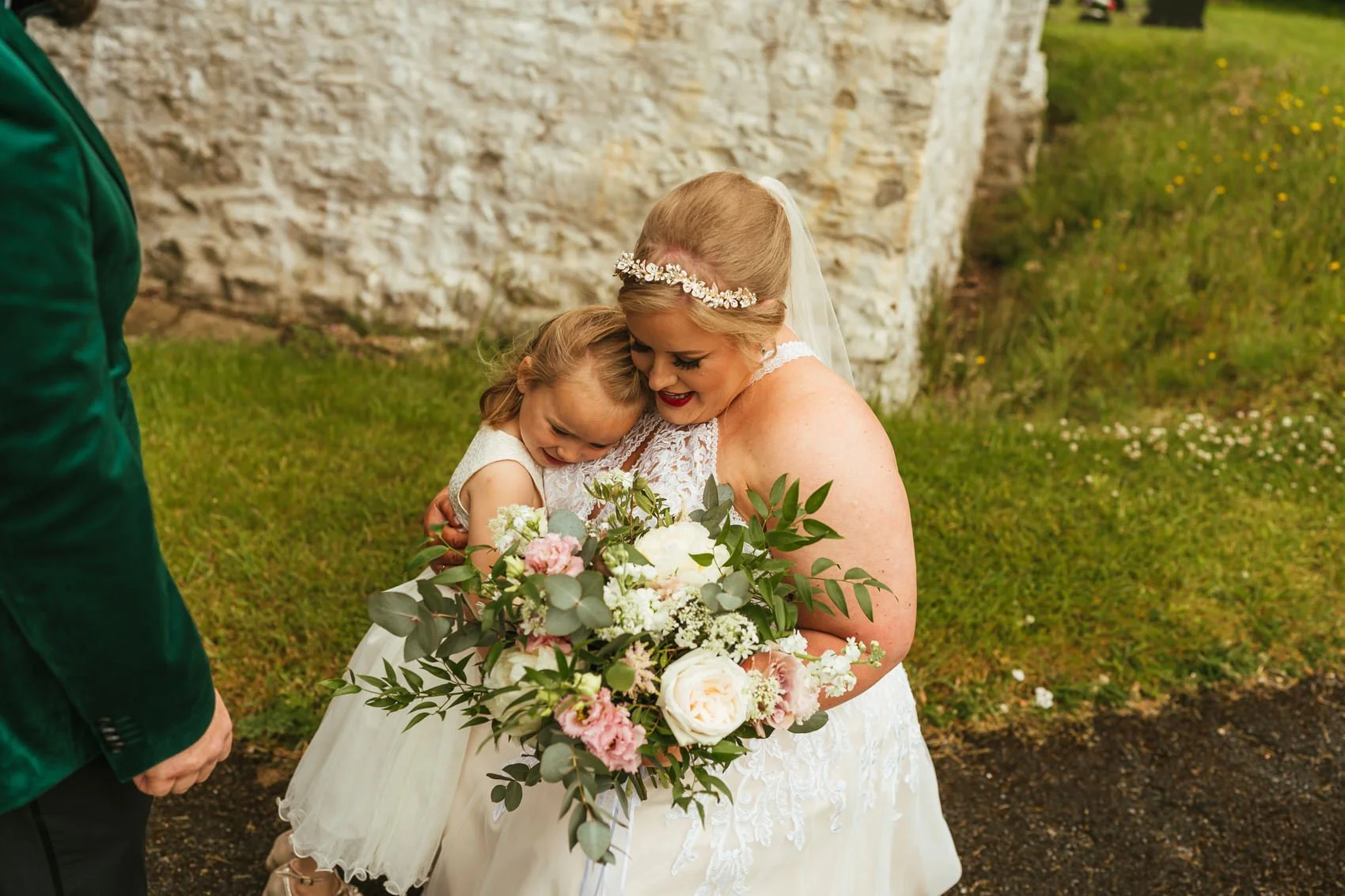Bride cuddling bridesmaid outside church
