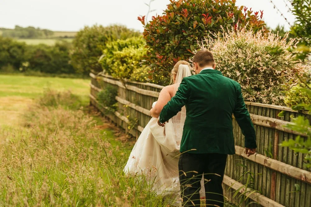 Bride and groom walking in meadow