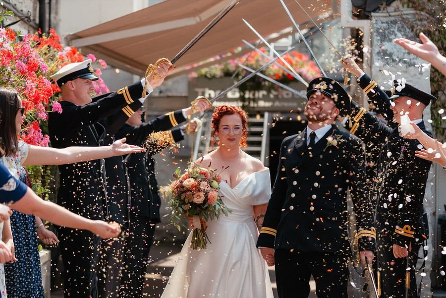 Royal Navy wedding, couple moment with a sword guard, the wedding couple walking through to a flutter of confetti outside the Bear Hotel in Cowbridge