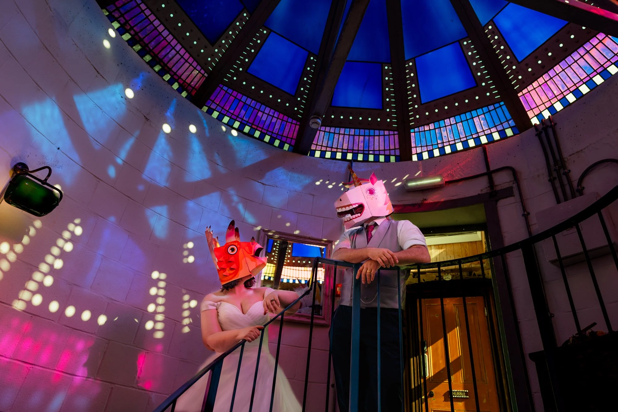 Wedding couple in Swansea observatory lit up by pink and blue lighting, wearing dungeons and dragons themed masks.