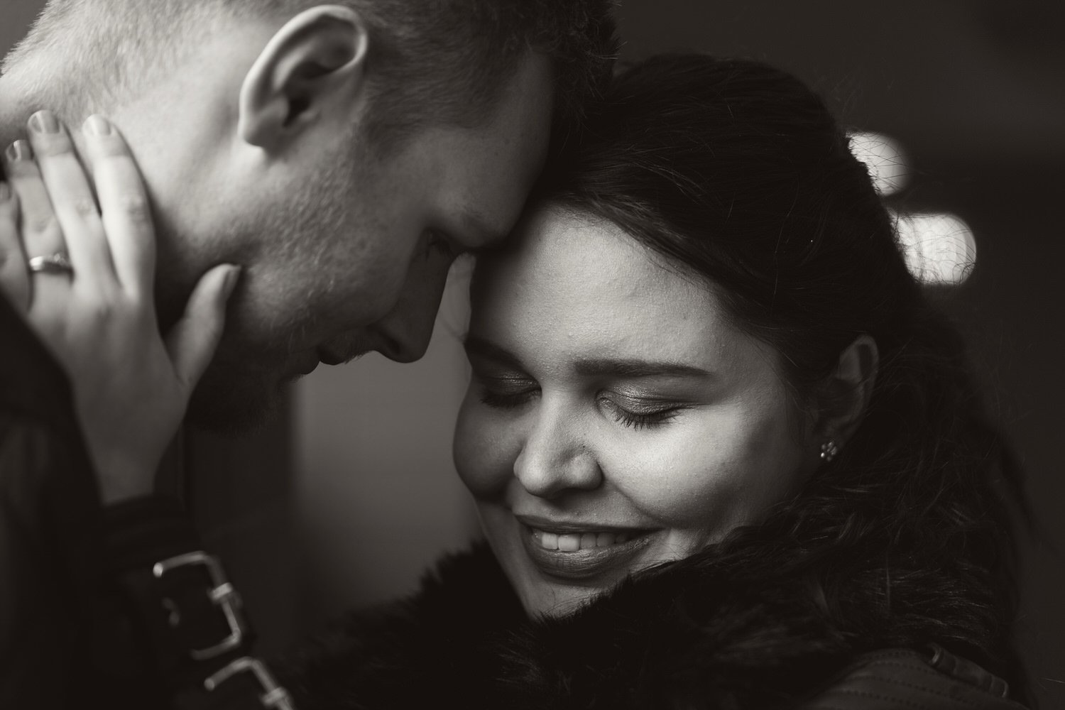Close up in black and white of an engaged couple cuddling in Swansea.