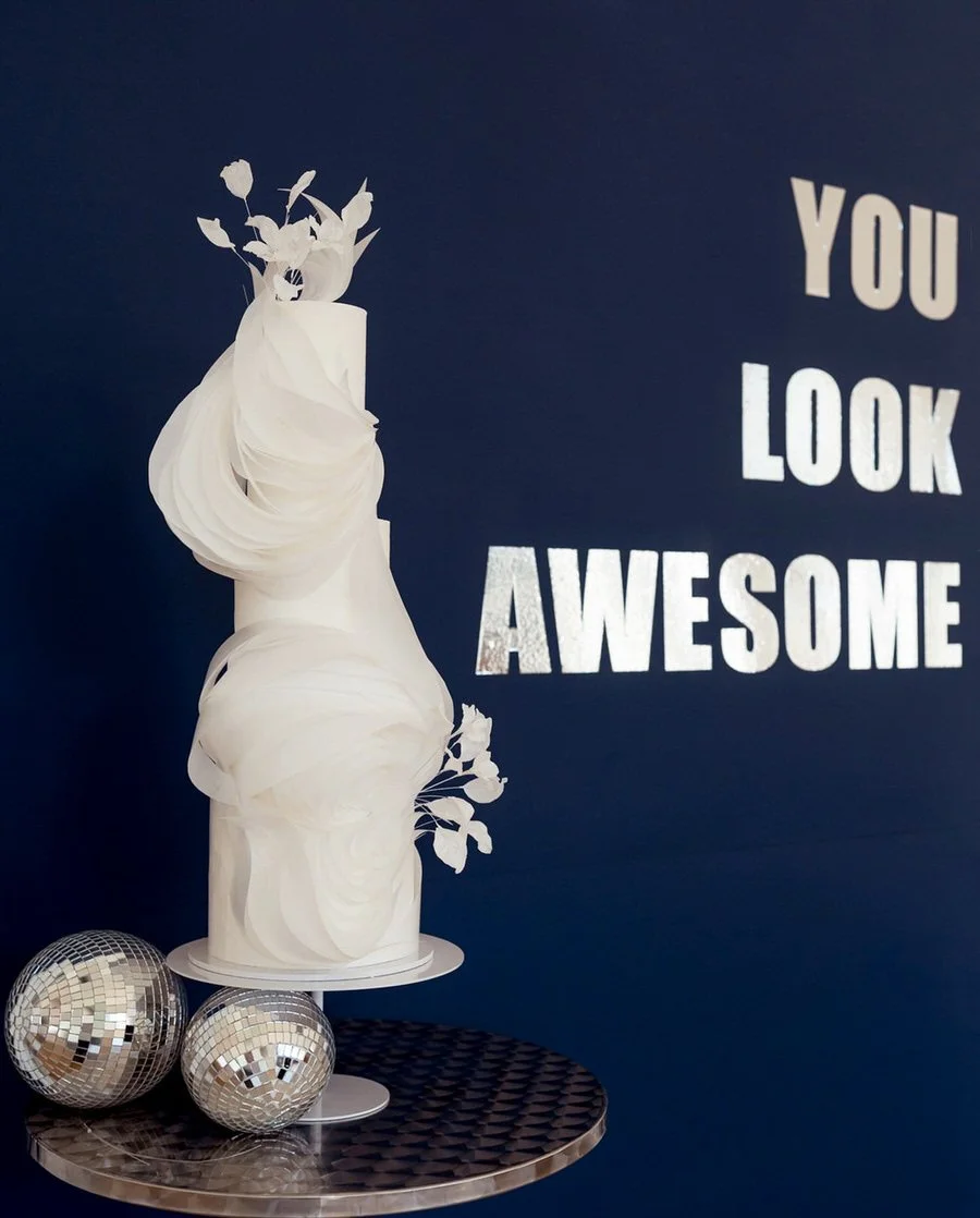 White ruffled artist three tier wedding cake against a navy background.