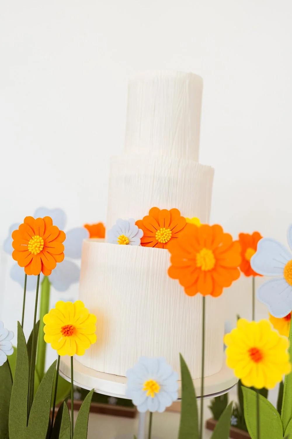 Funky Floral Felts  Playful white wedding cake surrounded by oversized colourful felt flowers